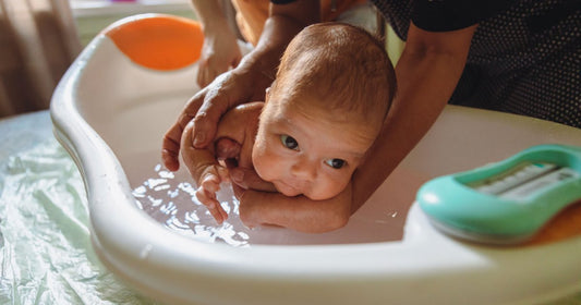 Parent donnant le bain à son bébé dans une baignoire bébé adaptée à l’âge et à l’espace disponible