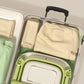 Baignoire bébé pliable verte rangée dans valise ouverte avec vêtements