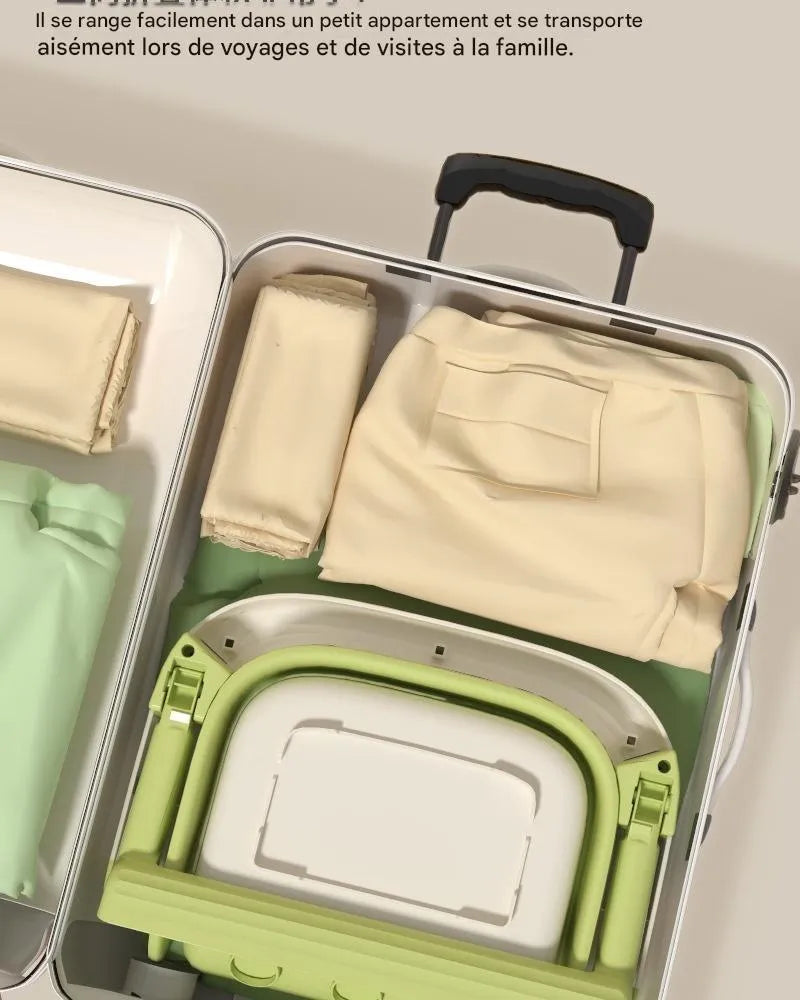 Baignoire bébé pliable verte rangée dans valise ouverte avec vêtements