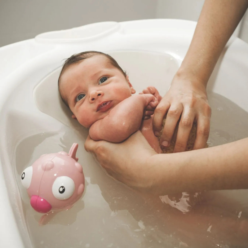 Parent donnant le bain à son bébé dans une ambiance calme et sécurisée
