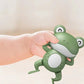 Jouet pour baignoire bébé en forme de grenouille dan la main d'un bébé.