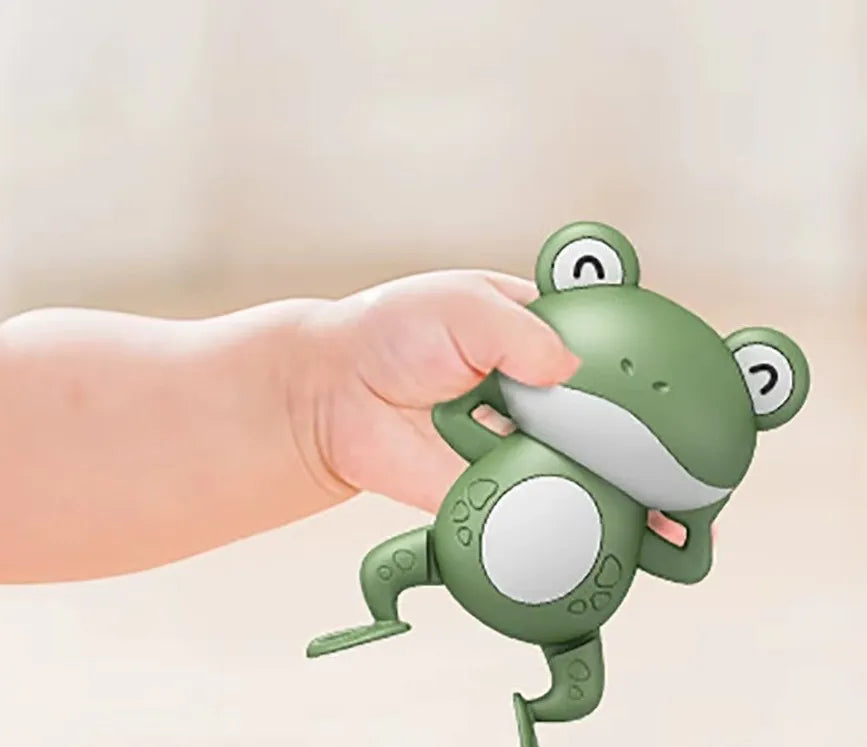 Jouet pour baignoire bébé en forme de grenouille dan la main d'un bébé.