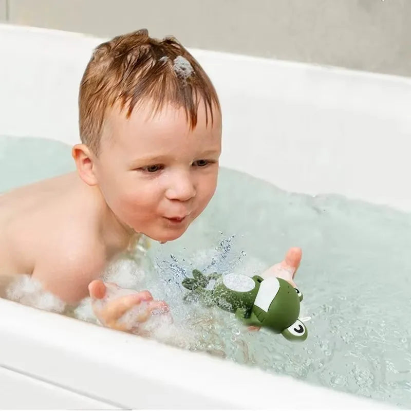 Bébé joue avec un jouet de baignoire. Il souffle dessus et le grenouille se met à bouger.
