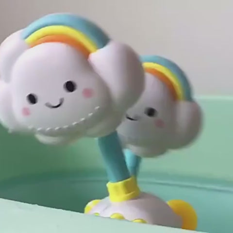 Bébé souriant dans baignoire avec jouet nuage douche arc-en-ciel qui projette l'eau