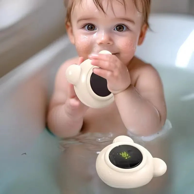 Bébé jouant dans le bain avec un thermomètre de bain ourson digital flottant